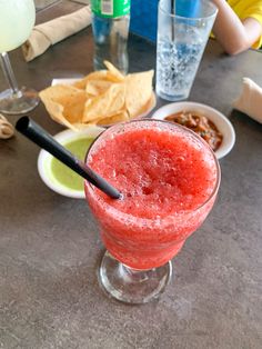 a red drink sitting on top of a table next to plates of food and drinks