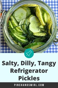 a jar filled with sliced cucumbers on top of a blue and white checkered table