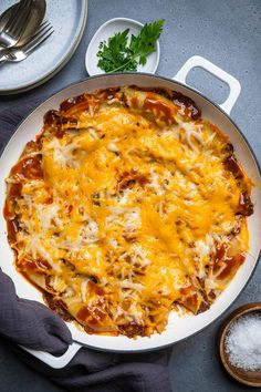 a cheesy dish is shown on a table with utensils