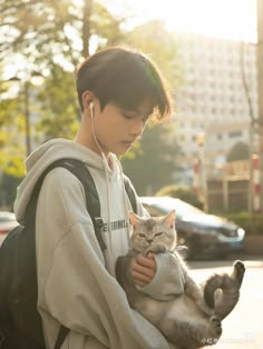 a young man holding a cat in his arms and listening to music on earphones