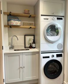 a washer and dryer in a small room with open shelving on the wall