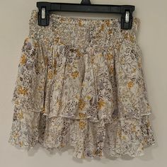 Cream Floral Skirt With Yellow Purple And Brown Flower Design And Textured Fabric Super Cute Layered Floral Skirt Perfect For Summer And As A Beach Or Pool Coverup Perfect Condition Never Worn Completely New Elastic Waist Super Comfy And Flattering Size M Length About 13.5 Inches Waist About 11.5 No Damage, Rips Or Stains From A Smoke Free And Pet Free Clean Household Reasonable Offers Are Welcome :) Feel Free To Ask Me Questions Below White Bohemian Mini Skirt With Floral Print, Bohemian White Mini Skirt With Floral Print, Flowy Floral Print Mini Skirt, Yellow Tiered Skirt With Floral Print, Yellow Tiered Skirt With Elastic Waistband, Flowy Yellow Ruffled Skirt, Yellow Floral Print Skirt, Yellow Tiered Mini Skirt For Summer, Yellow Bohemian Bottoms With Ruffled Skirt