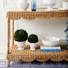 two potted plants sit on a wicker shelf next to blue and white vases