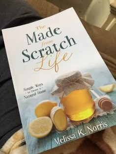 a book about the made from scratch life is sitting on someone's lap and holding it