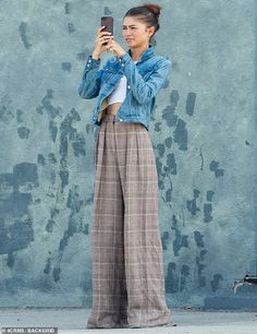 a woman standing in front of a blue wall taking a selfie with her cell phone