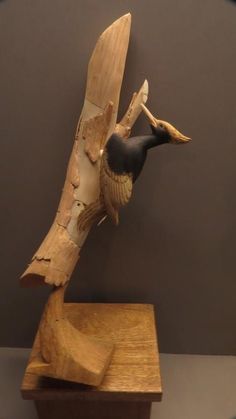 a wooden sculpture of a bird perched on a branch