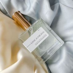 a bottle of perfume sitting on top of a white cloth next to a wooden stick