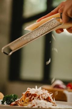 a person is grating cheese on top of some pasta and broccoli with a grater