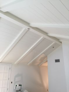 an unfinished room with white walls and wood beams on the ceiling is being worked on