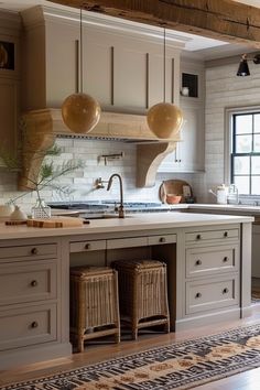 a kitchen with an island, sink and two hanging lights over the stove top area