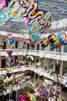 many colorful kites are hanging from the ceiling in a large room with high ceilings