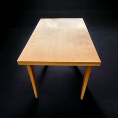 a small wooden table sitting on top of a black floor