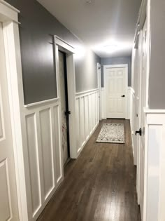 an empty hallway with wood floors and white trim on the walls is seen in this image