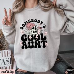 Get ready to be OBSESSED with your new 'Somebody's Cool Aunt' sweatshirt. It's the cutest and most trendy way to emit all those important Auntie vibes! This is the perfect Aunt sweatshirt! Great as an Auntie gift! * Q U I C K * F A C T S * ✺ 50/50 cotton polyester blend - so soft it feels like a cloud on your skin! ✺ Machine wash cold, inside out. Tumble dry low or hang to dry. Do not bleach, iron or dry clean. * S I Z I N G * ✺ Models are wearing XL for the oversized look ✺ Sizing is unisex so runs like men's, though not overly large ✺ Most women find their typical size works best for a more fitted look, since they are meant to fit a touch loose ✺ For the trendy oversized look, we recommend sizing up 1-2 sizes from your normal size ✺ Size guide and fit: See photos * P R O D U C T I O N * Fall Slogan Hoodie Top, Cool Cotton Winter Tops, Cool Cotton Tops For Winter, Cool Crew Neck Tops For Winter, Cool Long Sleeve Cotton Tops, Cool Sweatshirt With Letter Print, Cool Long Sleeve Relaxed Fit Tops, Cool Relaxed Fit Long Sleeve Tops, Relaxed Fit Long Sleeve Casual Top