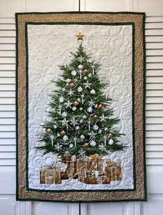 a quilted christmas tree with presents under it on a wall hanging in front of a white door