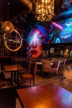 a brightly lit restaurant with wooden tables and colorful lights hanging from the ceiling above them