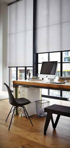 a desk with a computer on top of it next to two chairs and a window