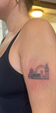 a woman with a small tattoo on her arm, and a clock tower in the background