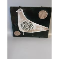 a white bird sitting on top of a black box next to flowers and balls in it