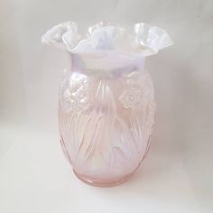 a pink glass vase sitting on top of a white table