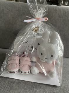 a pair of pink shoes and a stuffed bunny in a clear bag on a couch