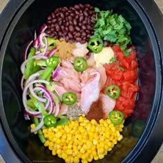 a black bowl filled with different types of vegetables and meats on top of each other