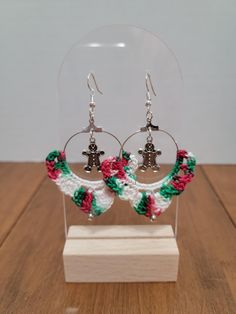 a pair of earrings with flowers and bells on them sitting in a clear display case