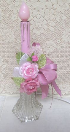 a pink candle and some flowers in a glass vase