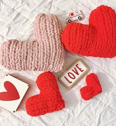 two knitted hearts, one with the word love next to it and some small magnets