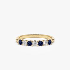 a yellow gold ring with three blue sapphire stones on the side and one white diamond in the middle