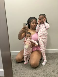 a woman is taking a selfie with her two babys in front of a mirror