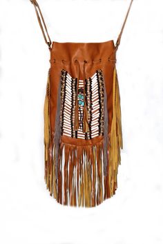 a brown leather purse with fringes and beads on the front, sitting on a white surface