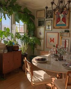 a dining room table surrounded by plants and pictures