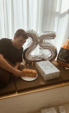 a man sitting in front of a table with a cake and number 25 on it