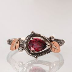 A handmade 14k twig and leaf ring made in two gold colors and set with a beautiful, natural ruby (you can also select a lab-grown ruby) Two small diamonds are set in 'berries' to add some sparkle to the ring. The grooves in the band are plated with black rhodium which emphasizes the texture. if you prefer not to apply the black rhodium that is fine. I can also use white, rose or yellow gold for the band and the leaves for the same price. The center stone is a 5mmX7mm natural red ruby of the highest quality. If you are looking at this ring then you are probably looking for something special, something different. The engagement rings I design are made of 100% recycled gold and non-conflict diamonds in high quality. After I am sure you have seen a huge variety of engagement rings I am guessin Leaf Wedding Ring, Natural Ruby Ring, Bridal Engagement Rings, Gold Colors, Leaf Ring, Black Rhodium, Red Ruby, Recycled Gold, Ruby Ring