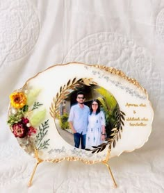 a couple is standing in front of a white table cloth with flowers and leaves on it