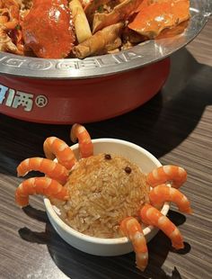 a bowl of rice and some crab legs on a table next to a plate of food