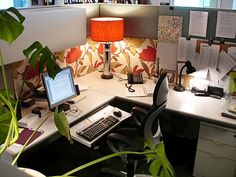 an office cubicle with two computers on the desk and a lamp in the corner