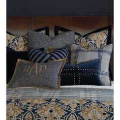 a bed with blue and gold comforter, pillows and pillow cases on top of it