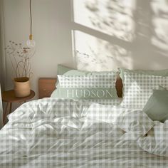 an unmade bed with green and white checkered sheets, pillows and pillowcases