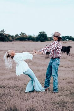 a man and woman dancing in an open field