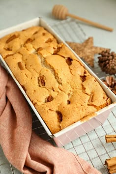 a loaf of bread sitting on top of a cooling rack next to cinnamon sticks and an orange towel