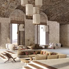 a living room filled with lots of furniture next to tall windows and stone wall coverings