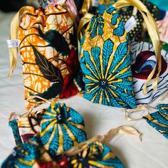 several colorful bags are sitting on a bed with ribbon around the handles and drawstring