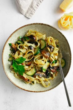 pasta with mushrooms, zucchini and parsley in a bowl on a white table