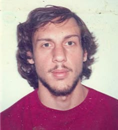 a man with long hair and beard wearing a red shirt