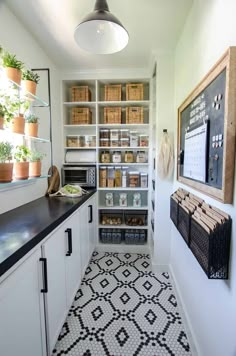 a kitchen with white cabinets and black counter tops next to a wall mounted chalkboard