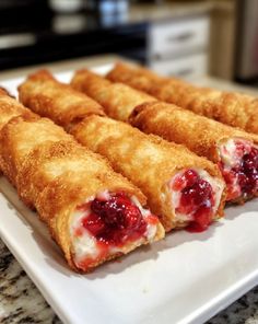 several crepes on a white plate with raspberry sauce and cheese filling