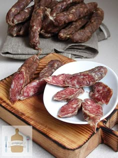 some sausages are on a white plate next to other food items and a wooden cutting board