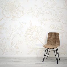 a wicker chair sitting in front of a wall with flowers painted on the walls